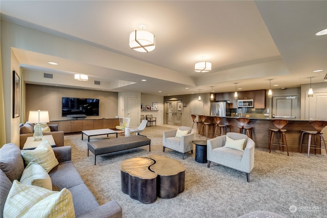 carpeted living room with a tray ceiling