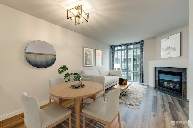 dining space with a wall of windows, wood-type flooring, and an inviting chandelier