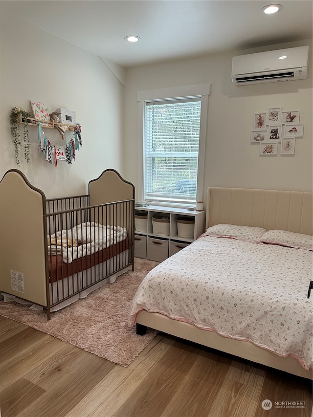 bedroom featuring wood-type flooring and a wall mounted air conditioner