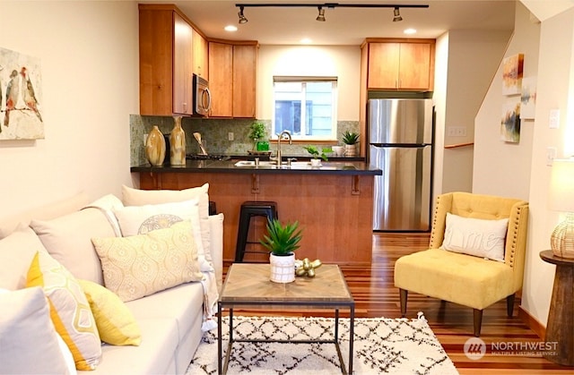 4333 9th Ave NE Unit C, Seattle, WA 98105 - interior space featuring backsplash, sink, light hardwood / wood-style flooring, appliances with stainless steel finishes, and kitchen peninsula