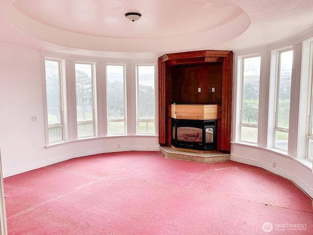 unfurnished living room featuring a raised ceiling and carpet floors