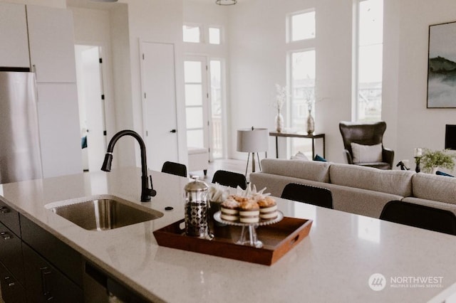 kitchen featuring white cabinetry, light stone countertops, sink, and stainless steel refrigerator