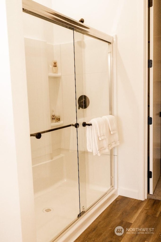 bathroom with hardwood / wood-style flooring and a shower with shower door