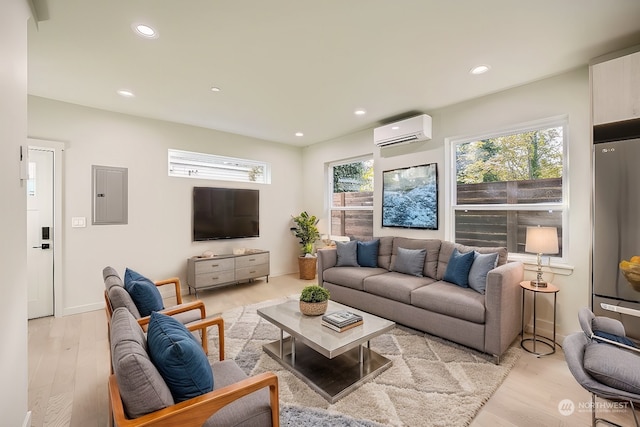 living room with electric panel, a wall unit AC, a wealth of natural light, and light hardwood / wood-style flooring