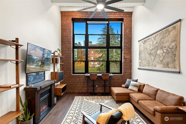 living room featuring ceiling fan, dark hardwood / wood-style flooring, and brick wall