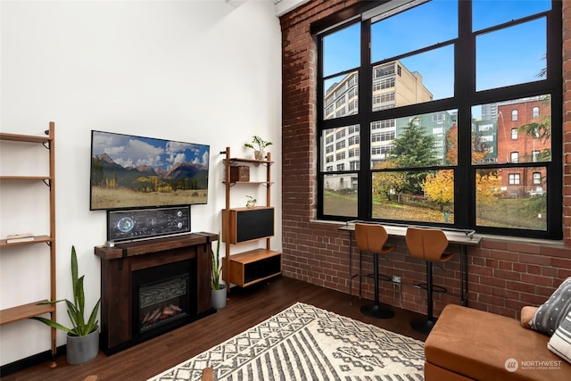 living room featuring dark hardwood / wood-style floors and brick wall