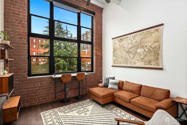 living room featuring dark wood-type flooring and brick wall