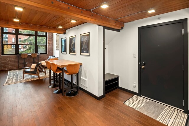 entrance foyer with wood ceiling, beamed ceiling, brick wall, and hardwood / wood-style flooring