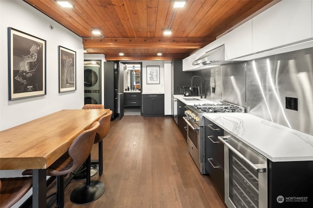 kitchen featuring wooden ceiling, stainless steel stove, stacked washing maching and dryer, dark hardwood / wood-style floors, and white cabinets