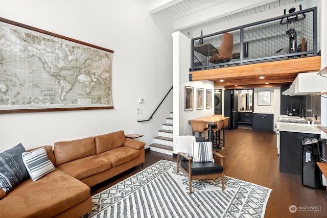 living room with beam ceiling, stacked washing maching and dryer, and dark hardwood / wood-style floors