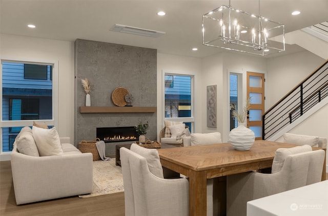 dining space with a large fireplace, hardwood / wood-style flooring, and a notable chandelier