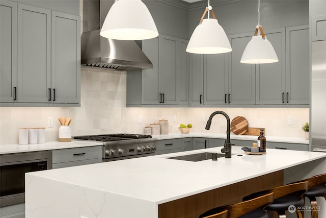 kitchen featuring decorative backsplash, wall chimney range hood, hanging light fixtures, and stainless steel range