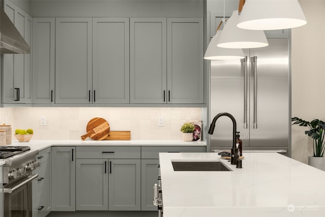 kitchen featuring sink, wall chimney exhaust hood, decorative light fixtures, gray cabinets, and high quality appliances