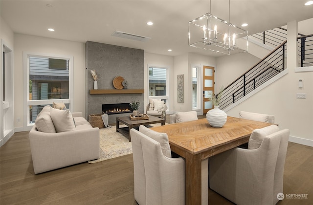 dining space featuring a large fireplace, dark wood-type flooring, and a chandelier