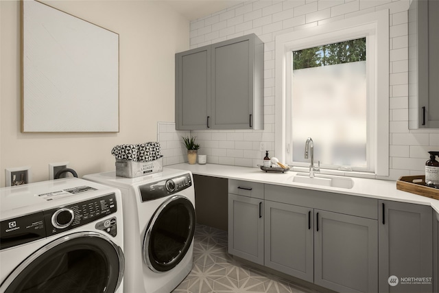 clothes washing area featuring cabinets, washing machine and clothes dryer, and sink