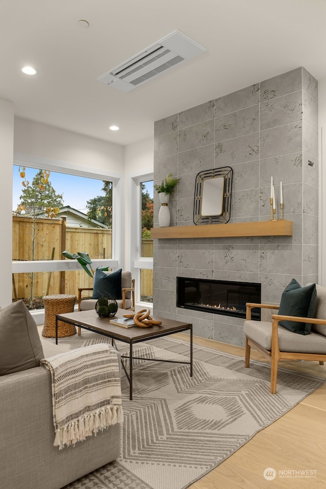 living room featuring hardwood / wood-style floors, tile walls, and a tile fireplace