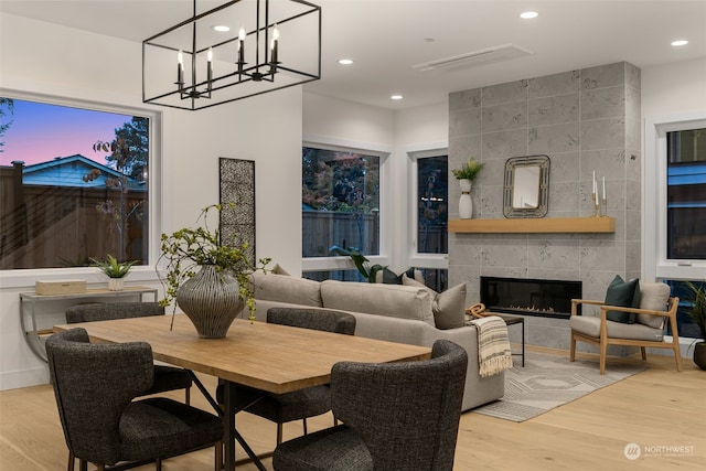 dining area with light wood-type flooring and a tiled fireplace