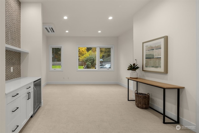 kitchen featuring white cabinets, backsplash, beverage cooler, and light carpet