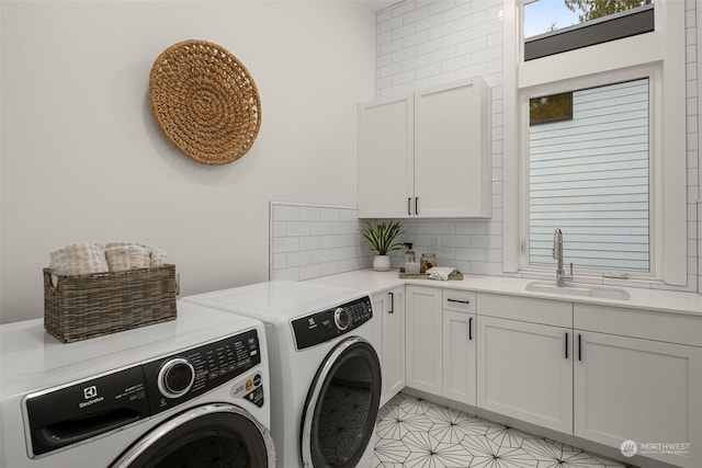 laundry area with washing machine and clothes dryer, cabinets, and sink