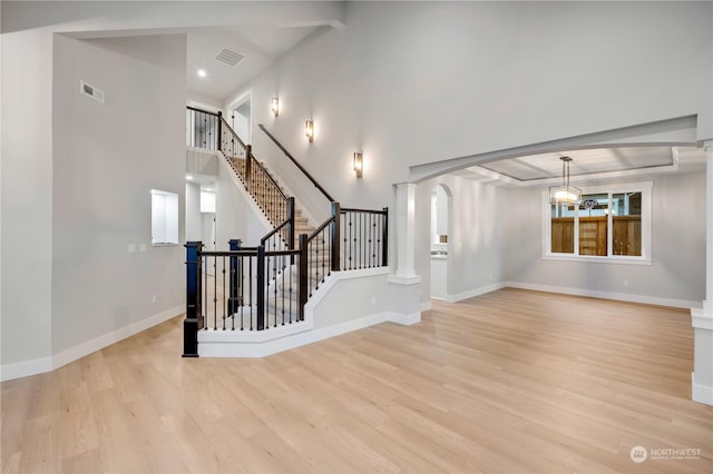 interior space with a chandelier, a towering ceiling, and light hardwood / wood-style floors