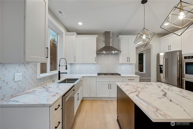 kitchen featuring white cabinets, wall chimney exhaust hood, sink, and stainless steel appliances