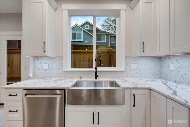 kitchen with stainless steel dishwasher, backsplash, white cabinetry, and sink