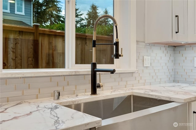 details featuring light stone countertops, sink, and white cabinets