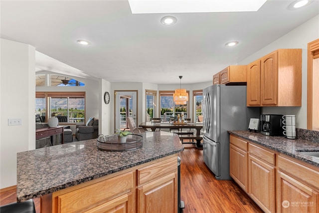 kitchen featuring stainless steel fridge, ceiling fan, decorative light fixtures, a center island, and dark hardwood / wood-style floors