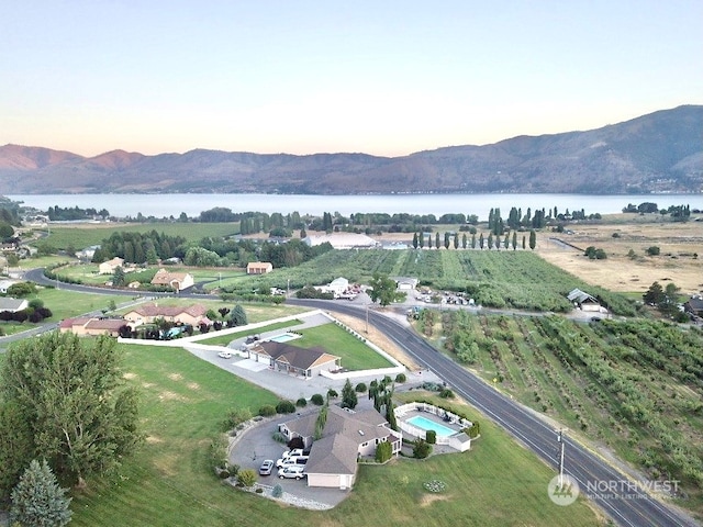 aerial view at dusk featuring a water and mountain view