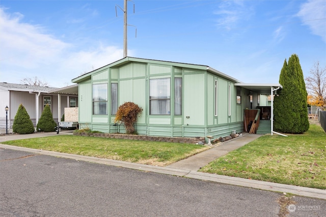 manufactured / mobile home with a front lawn and a carport