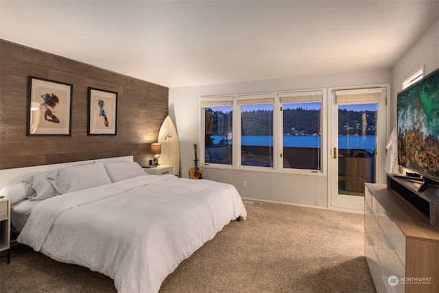 carpeted bedroom featuring access to exterior and wood walls