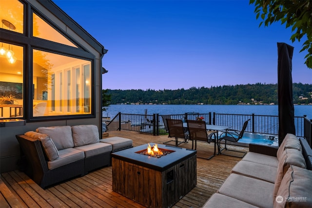 deck at dusk featuring a water view and an outdoor living space with a fire pit