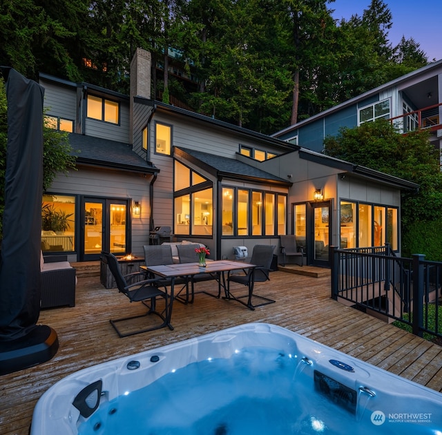 back house at dusk featuring a wooden deck