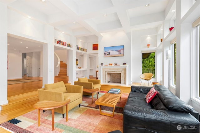 living room with beamed ceiling, wood-type flooring, a towering ceiling, and coffered ceiling