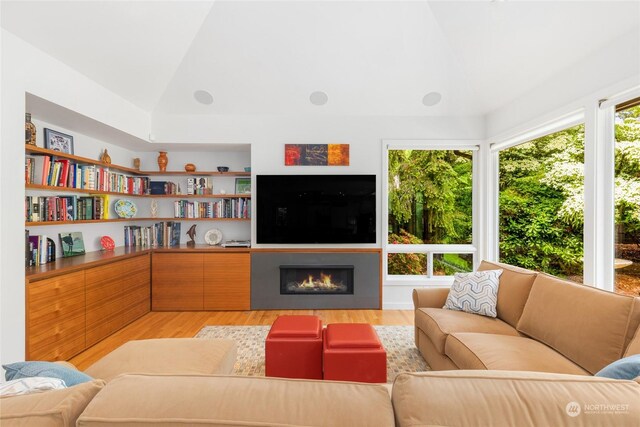 7842 NE 10th St, Medina, WA 98039 - living area featuring lofted ceiling, light wood finished floors, and a warm lit fireplace