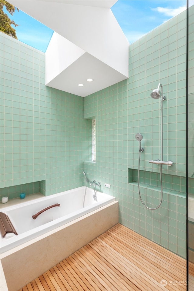 bathroom featuring plus walk in shower, wood-type flooring, and tile walls