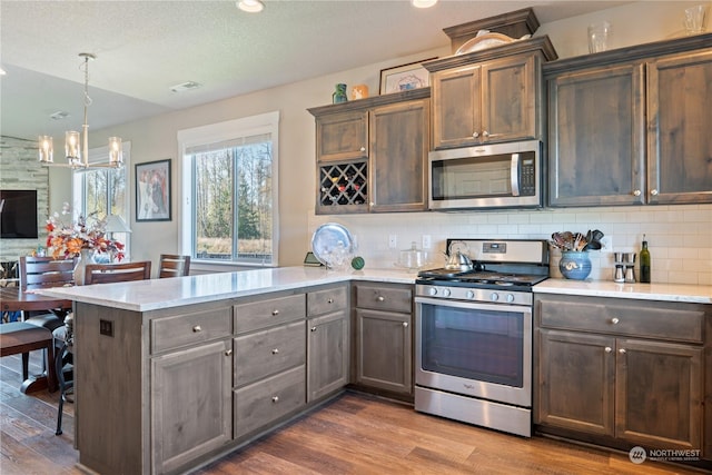 146 Zephyr Dr, Silverlake, WA 98645 - kitchen with stainless steel appliances, a peninsula, a chandelier, dark wood-type flooring, and tasteful backsplash