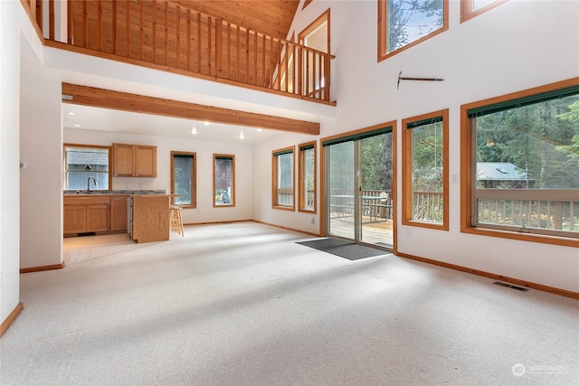 unfurnished living room with light colored carpet and a high ceiling