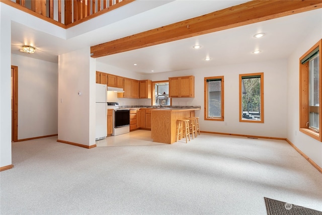 kitchen with a breakfast bar, white appliances, light carpet, sink, and beamed ceiling