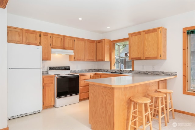 kitchen featuring kitchen peninsula, a kitchen breakfast bar, white appliances, and sink