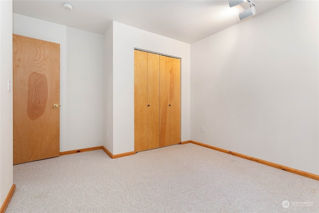 unfurnished bedroom featuring light colored carpet and a closet