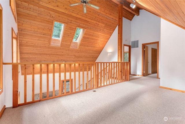 additional living space featuring a skylight, light colored carpet, high vaulted ceiling, wooden ceiling, and beamed ceiling