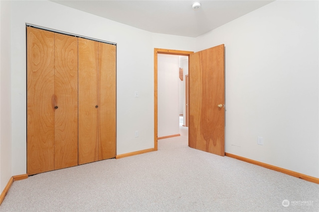 unfurnished bedroom featuring light colored carpet and a closet