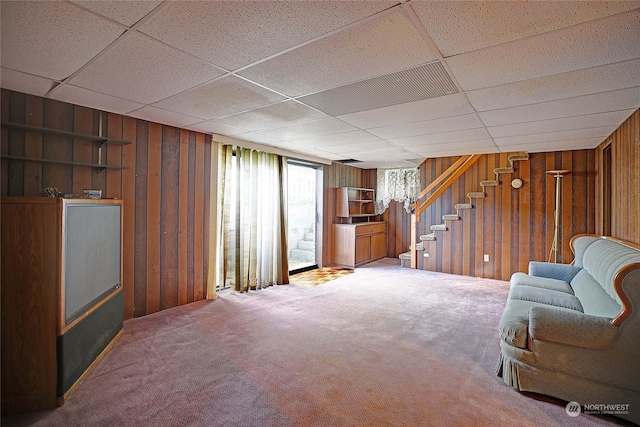 interior space featuring wood walls, a drop ceiling, and carpet floors