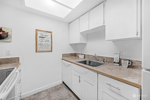 kitchen with white appliances, white cabinetry, and sink