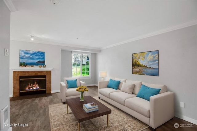 living room featuring wood-type flooring, ornamental molding, and a tile fireplace