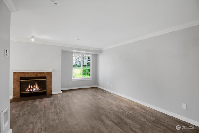 unfurnished living room with wood-type flooring, crown molding, and a tiled fireplace