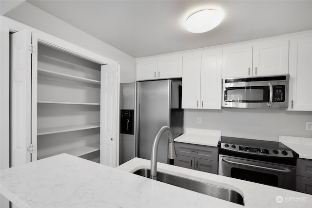 kitchen with white cabinets, sink, gray cabinets, light stone countertops, and stainless steel appliances