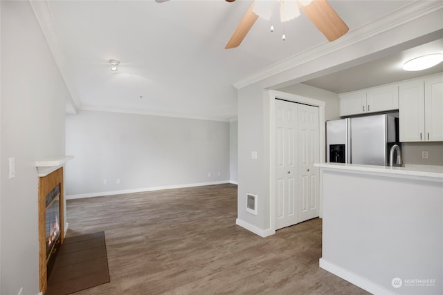 unfurnished living room with crown molding, ceiling fan, and light hardwood / wood-style floors