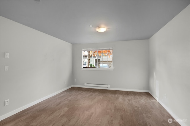 spare room with light wood-type flooring and a baseboard heating unit